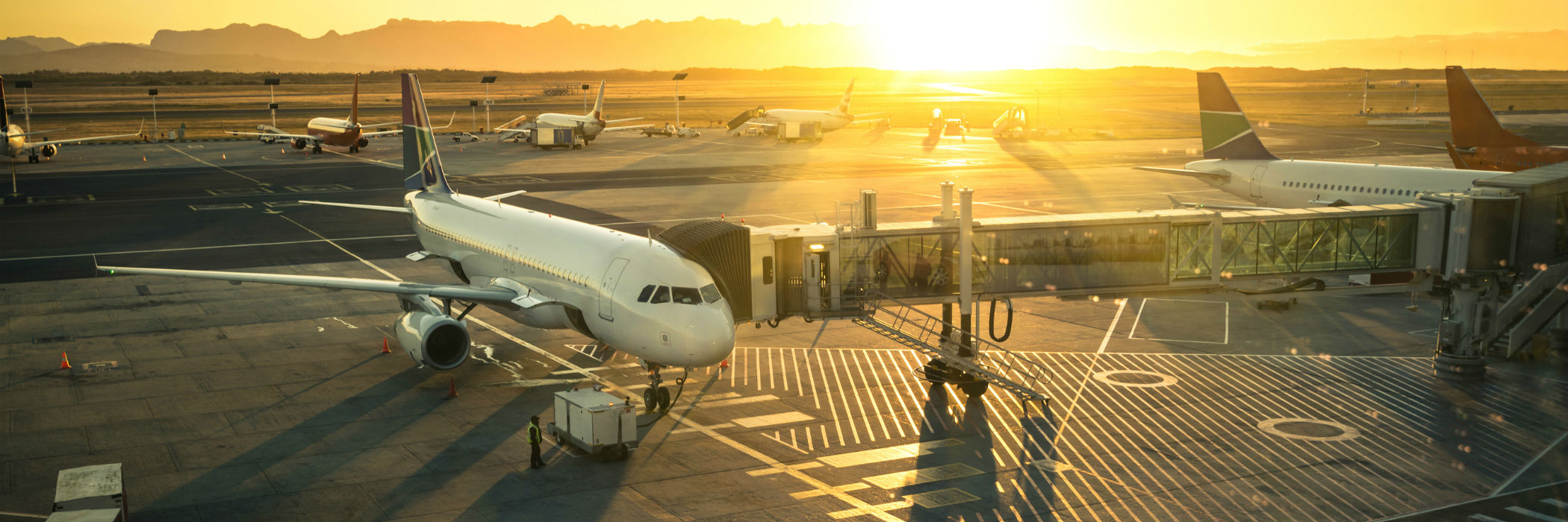 Airplanes and jet bridge at sunset