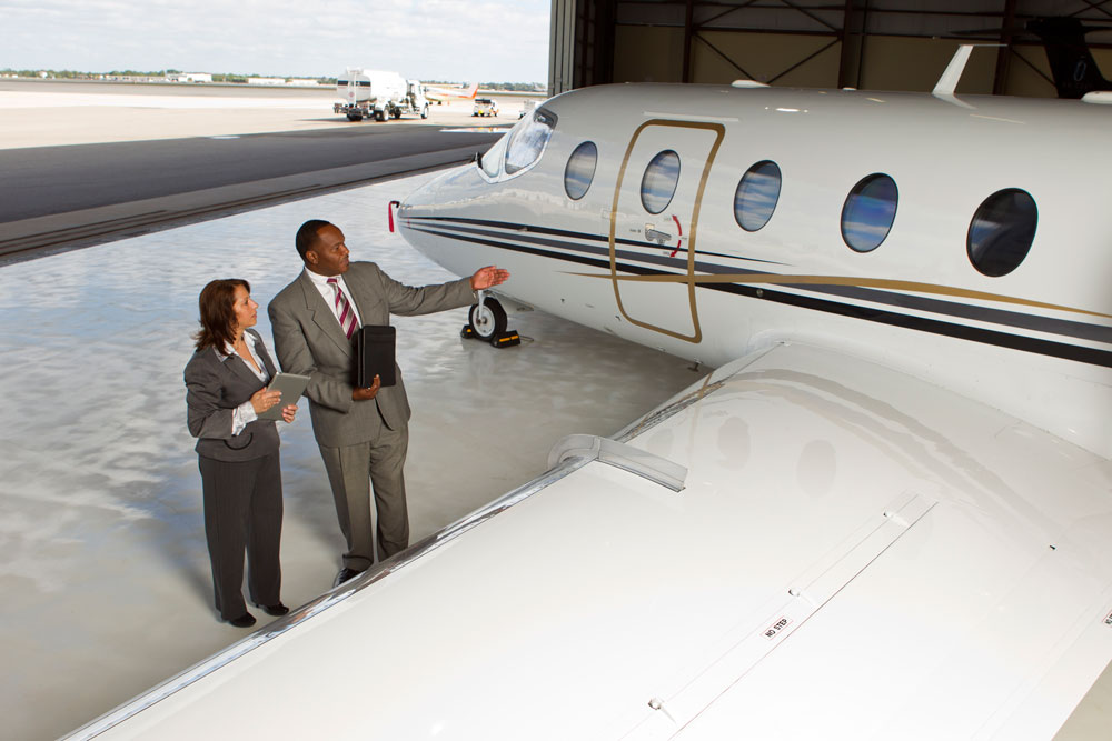 Two people discussing private jet in hangar