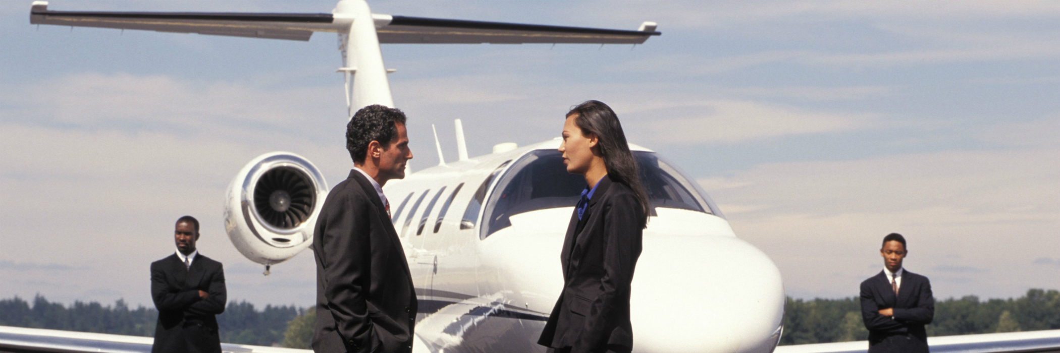 Businesspeople talking on runway in front of private jet