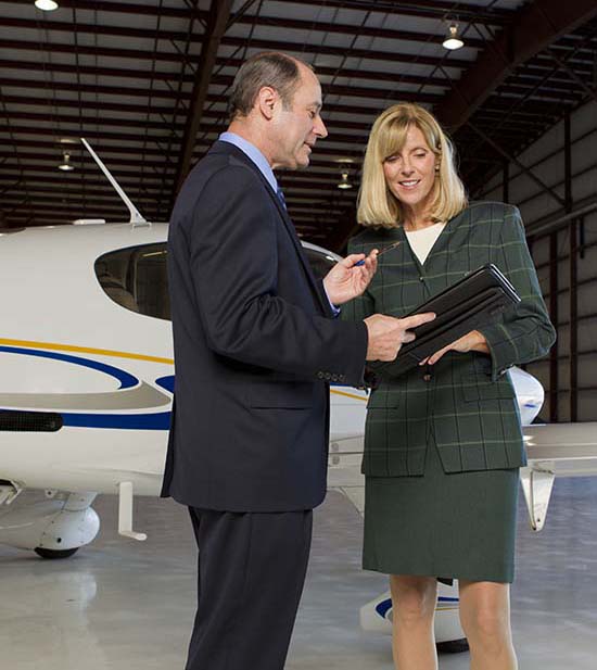 Two businesspeople consulting in front of small plane in hangar