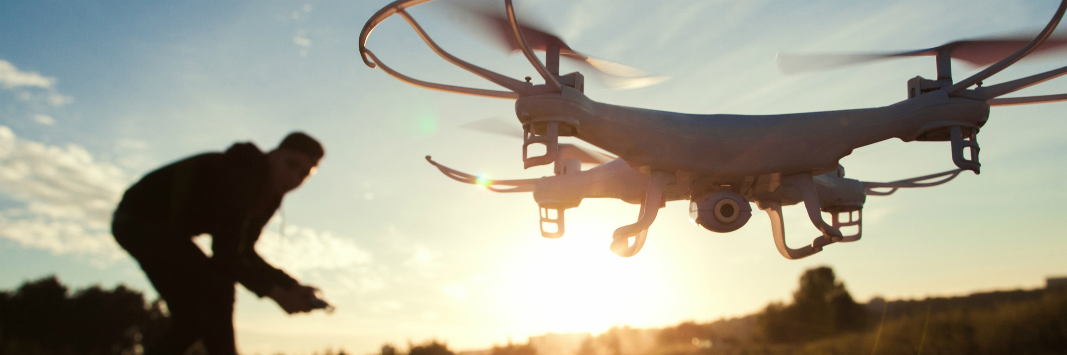 Silhouettes of pilot and hovering sUAS at sunrise