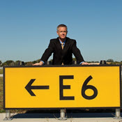 Man standing behind airport runway sign