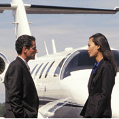 Businesspeople talking on runway in front of private jet