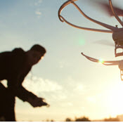 Silhouettes of pilot and hovering sUAS at sunrise