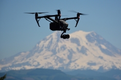 A drone flies in front of a mountain