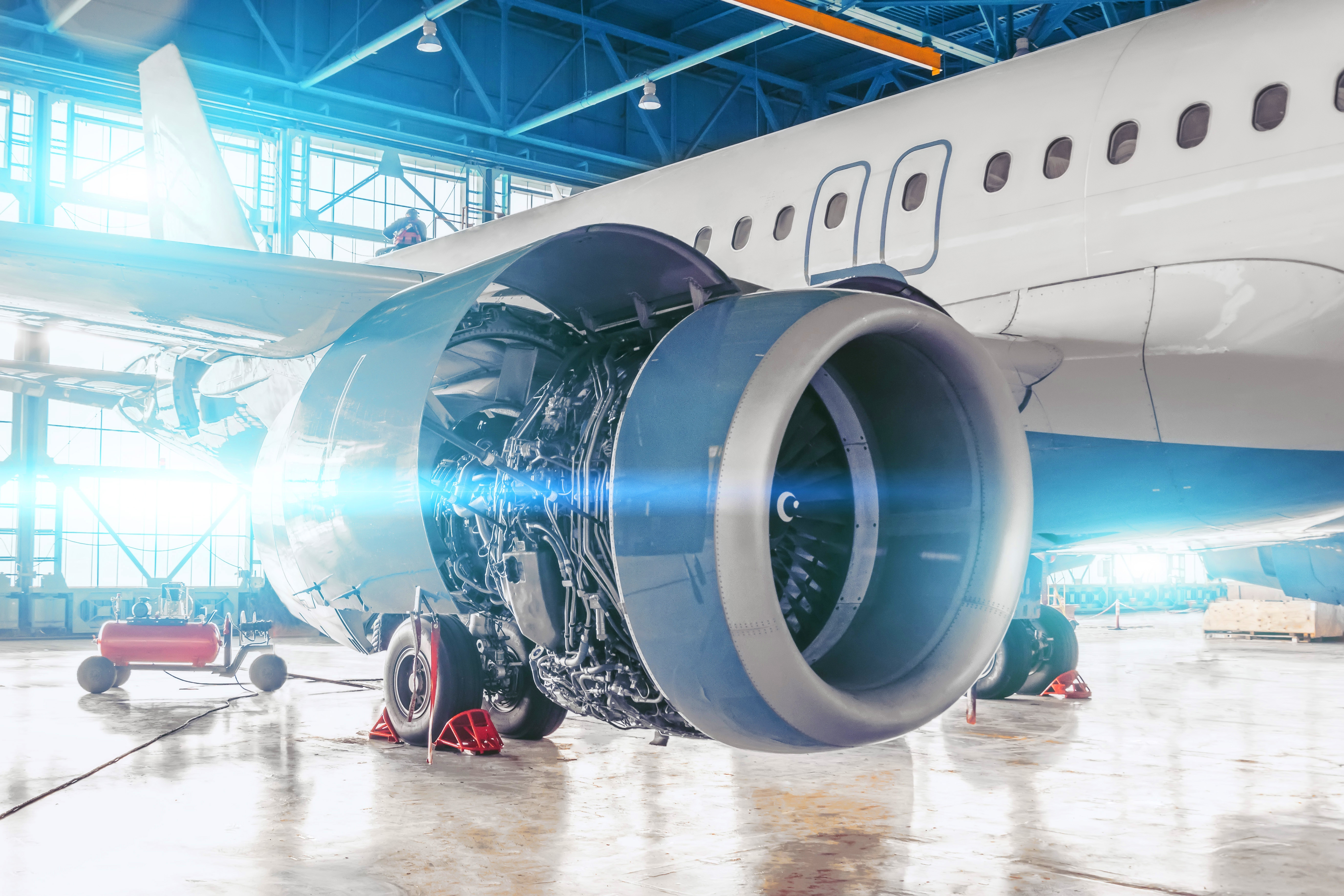 Repair and maintenance of aircraft jet engine with hood open on the wing.