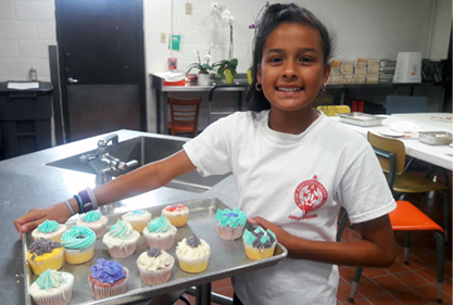 girl with pan of cupcakes;