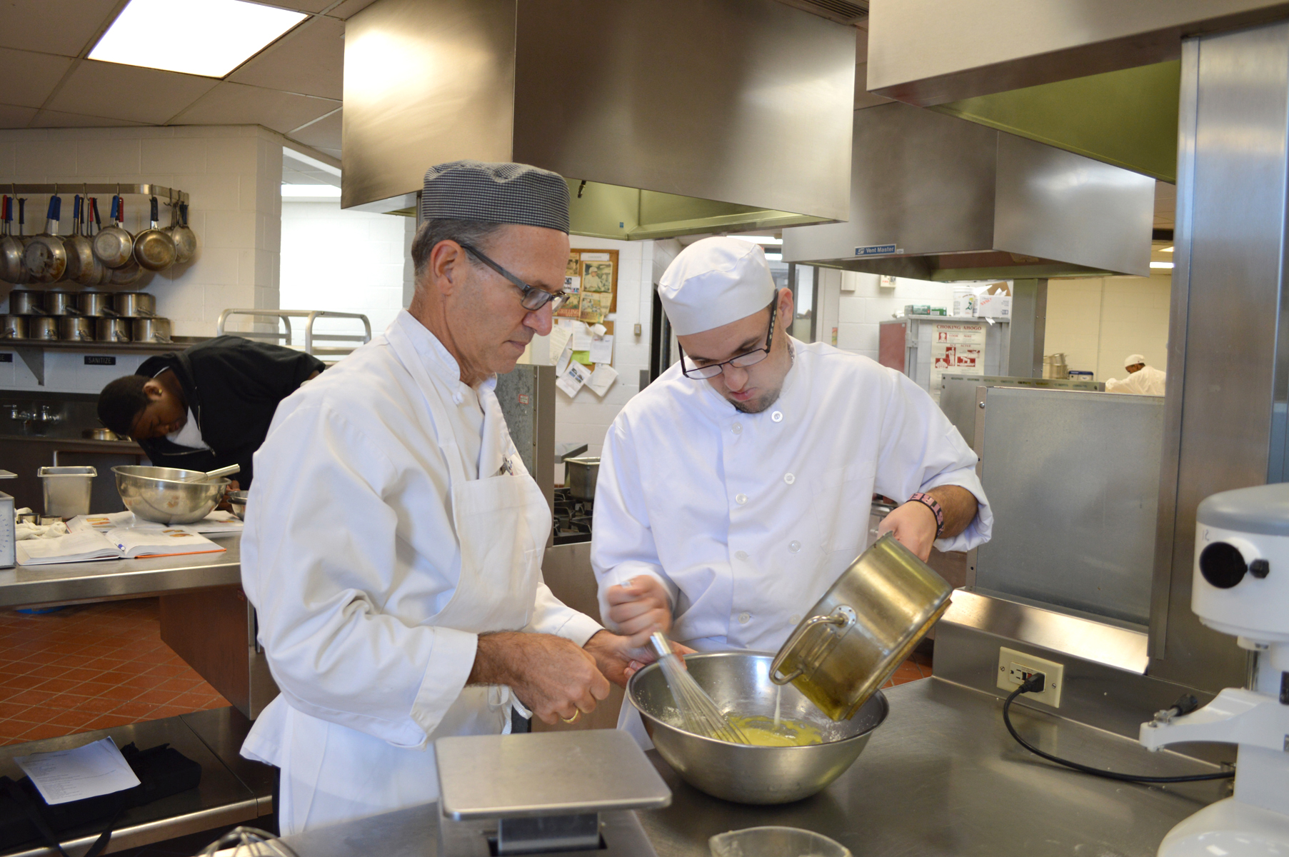 Two male chefs preparing sauce;